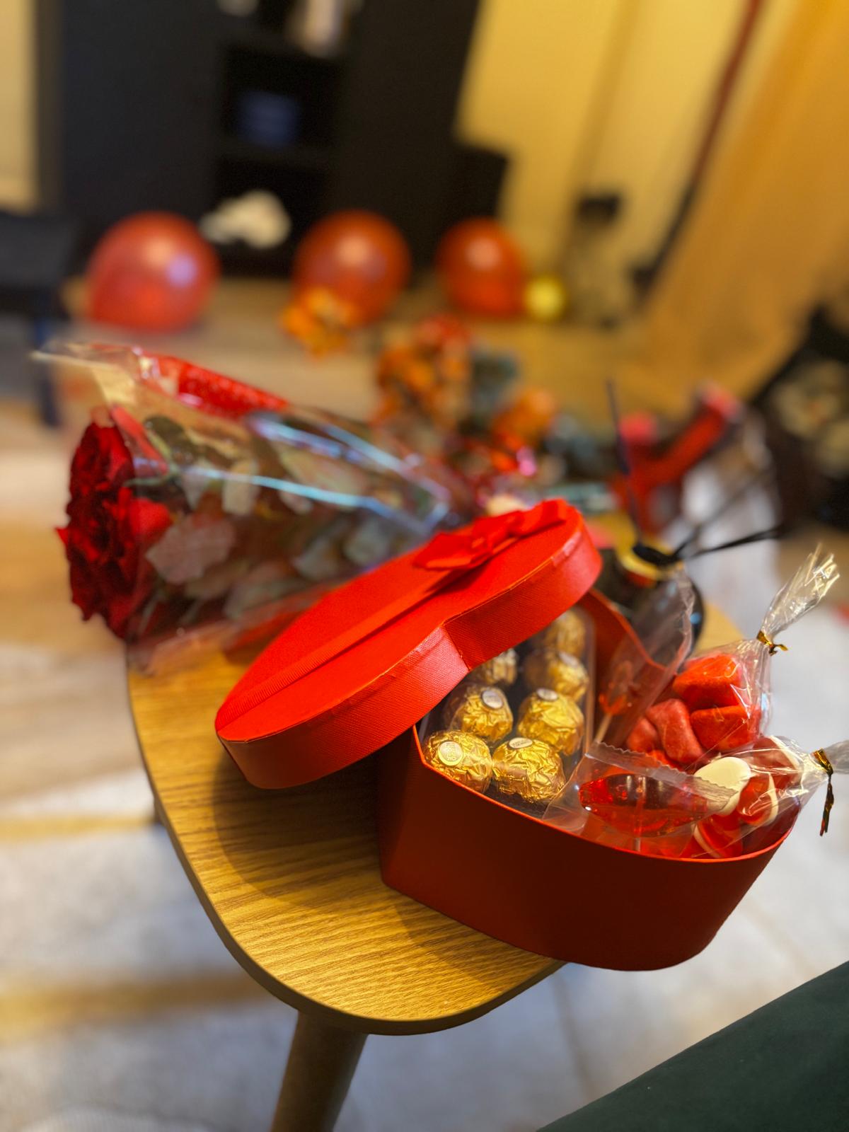Heart-shaped gift box with chocolates, sweets and a rose bouquet