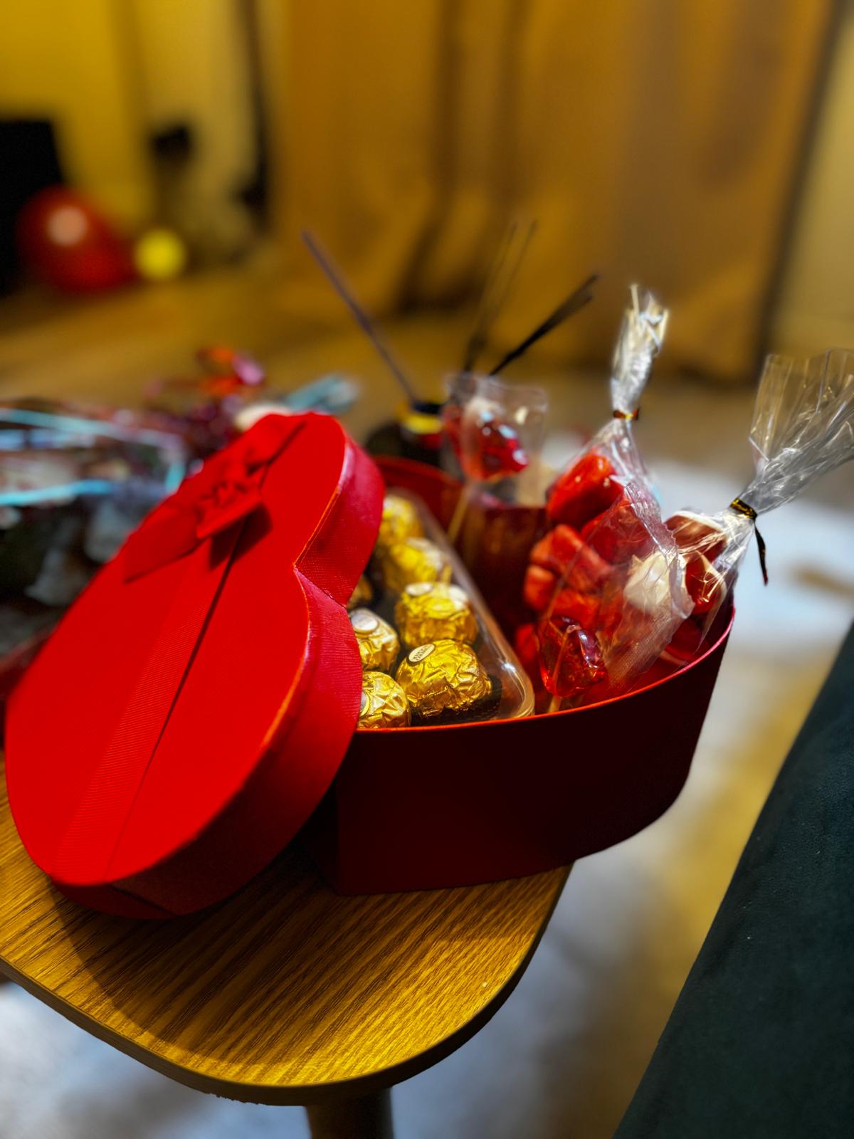 Gros plan du coffret cœur rouge avec chocolats dorés et sachets de bonbons